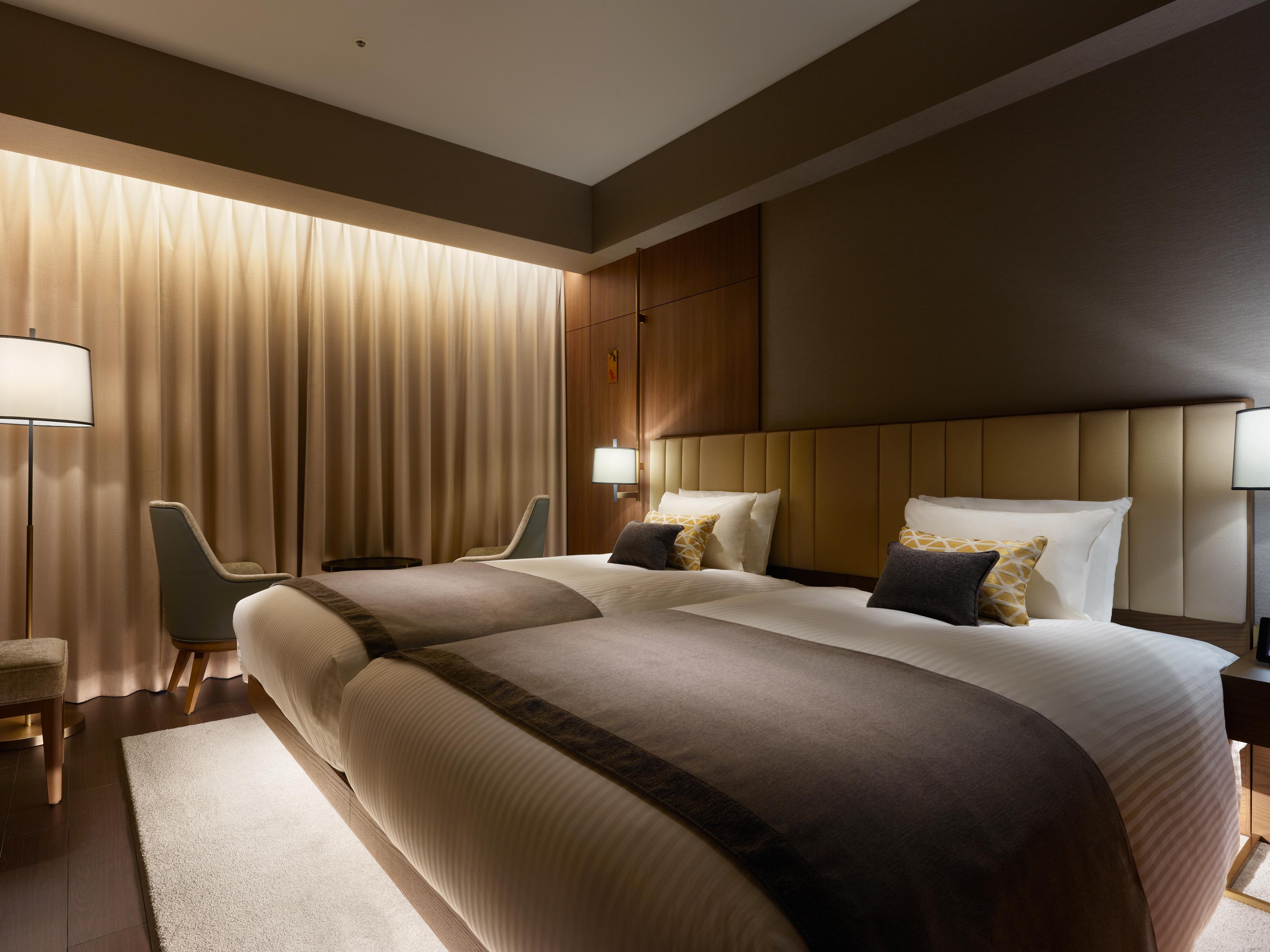 Mitsui Garden Hotel Roppongi Tokyo Premier Экстерьер фото The photo shows a modern hotel room featuring two twin beds with elegant bedding. The room is adorned with soft, neutral tones and has a warm ambiance created by subtle lighting. A pair of bedside lamps provide additional light, and there is a cozy c